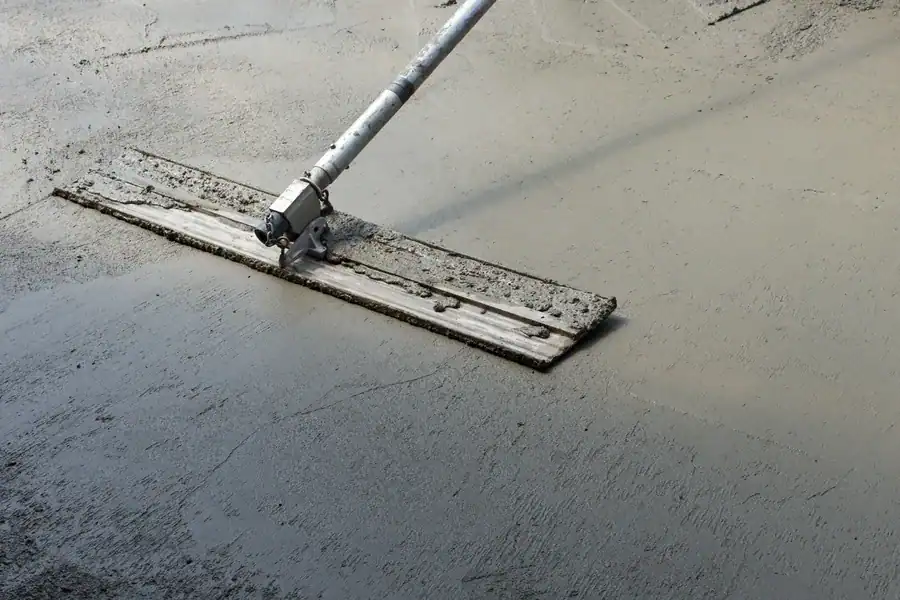 Vakman egaliseert vloeibare egaline op betonnen ondervloer als voorbereiding voor een gietvloer